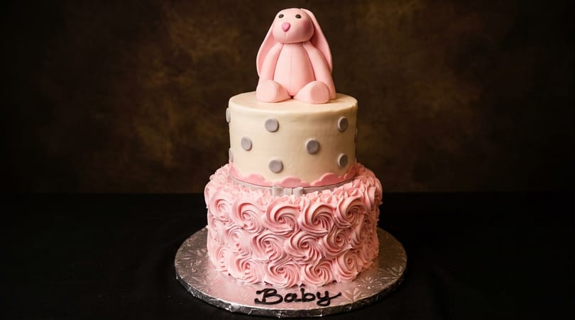 Two-tier pink and white cake with a pink bunny on top, and "Baby" written on the base.
